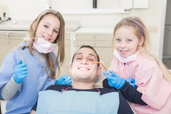 Little dentists examining the mouth of an adult patient — Stock Photo, Image