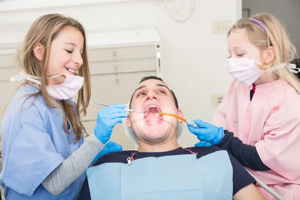 Little dentists examining the mouth of an adult patient — Stock Photo, Image