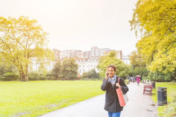 Young woman talking on the phone at park in London — Stock fotografie