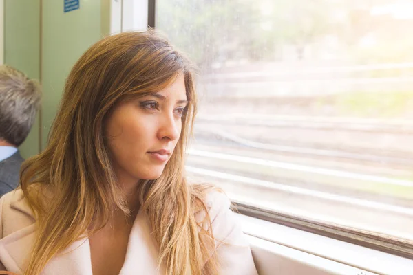 Güzel ve genç birbayan tren pencereden dışarı bakıyor — Stok fotoğraf