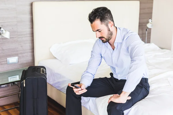 Businessman looking at smart phone in his hotel room — Stock Fotó