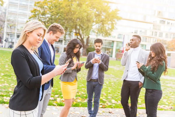 Group of people outdoor looking at their own smart phones — Stockfoto