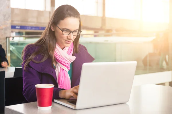 Young woman working with computer in a train station or airport — Stock Photo, Image