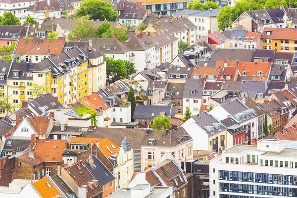 Aerial view of houses and rooftops in Cologne, Germany. Many of them are colourful, some are older and not painted. There are some trees in the gardens. Central Europe architecture.