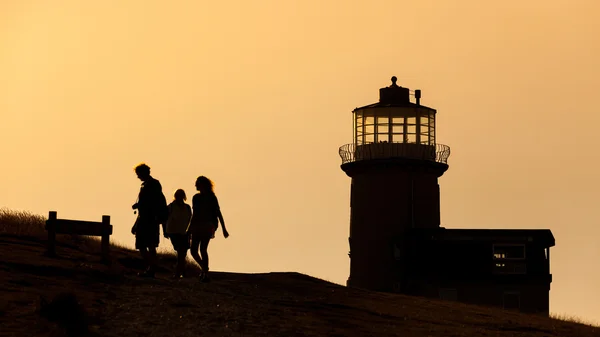 Silhouet van sommige mensen en een vuurtoren in Engeland — Stockfoto