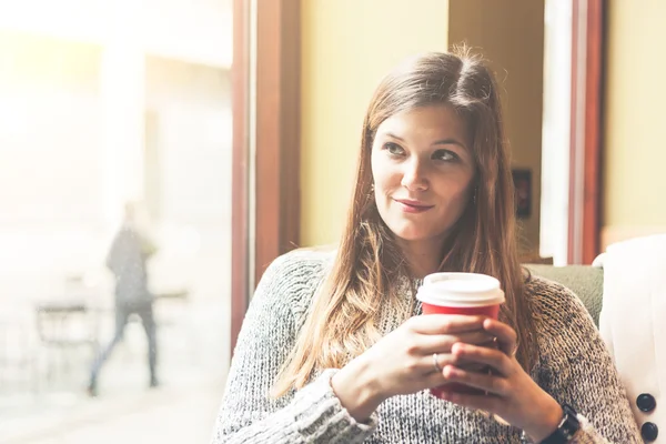 Beautiful woman in a cafe holding a cuf of tea — Stock Photo, Image