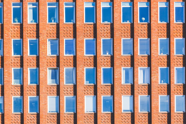 Building facade made of orange bricks and windows, with columns creating light and shadow effects. Photo taken in Oslo. It could be used as pattern or background for architecture purposes.