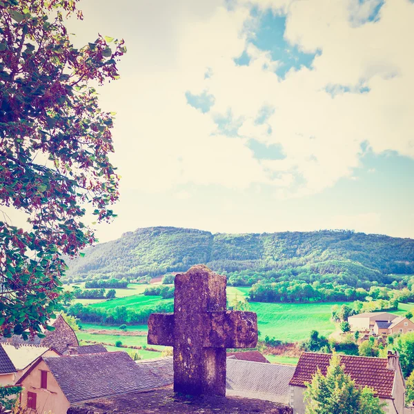 Каменный крест на фоне французского города — стоковое фото