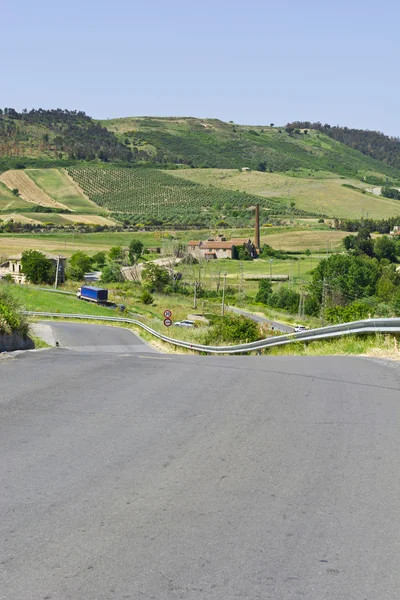 Camino de asfalto sinuoso entre los campos de Sicilia —  Fotos de Stock