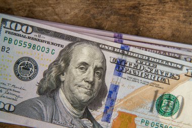 Yepyeni yüz dolarlık banknotlar eski ahşap bir masanın üzerinde duruyor. 