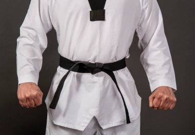 Tekvando için beyaz kimono giyen güçlü erkek atlet siyah kuşak sensei 'nin içinde duruyor.