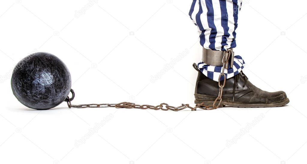 a leg of a prisoner in striped pants and a rough boot chained with an iron ball with shackles in profile 