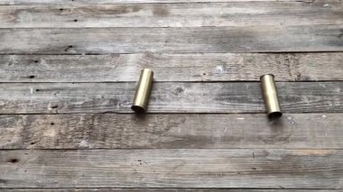 Eski bir av tüfeğinin iki metal kovanı ateş ettikten sonra buharlaşıp kaba ahşap bir zemine doluşmuş.