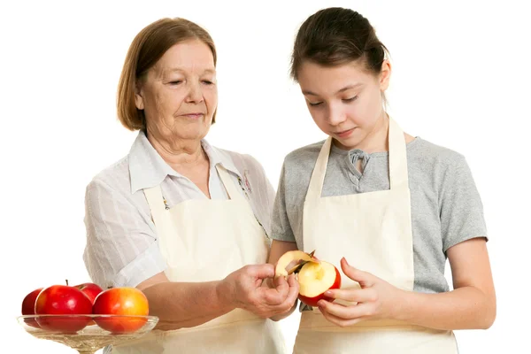 The grandmother teaches the granddaughter to cut off a peel from — Stock Photo, Image