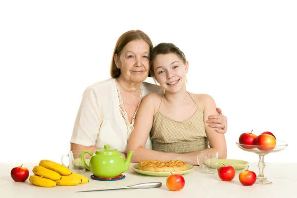 The grandmother and the granddaughter sit at a table — Stock Photo, Image