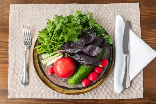 Hortalizas y hierbas en un plato sobre una mesa de madera — Foto de Stock