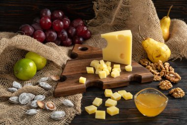 Tahta kesme tahtasındaki çeşitli peynir, armut ve fındık çeşitleri.