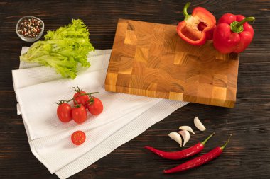 Tahta kesme tahtasında taze sebzeler, otlar ve baharatlar.