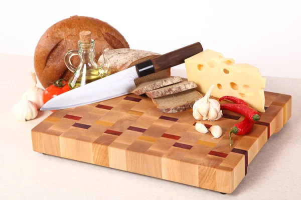 Vegetables, cheese and bread on a chopping board — Stock Photo, Image