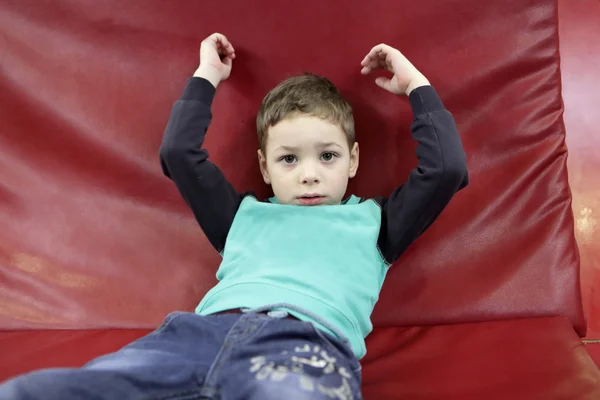 Enfant sur un canapé rouge — Photo