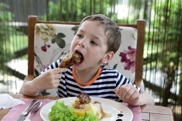 Criança comendo perna de frango — Fotografia de Stock