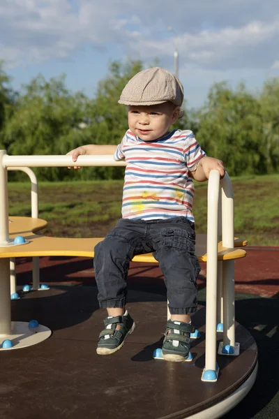 Niño sentado en la rotonda —  Fotos de Stock