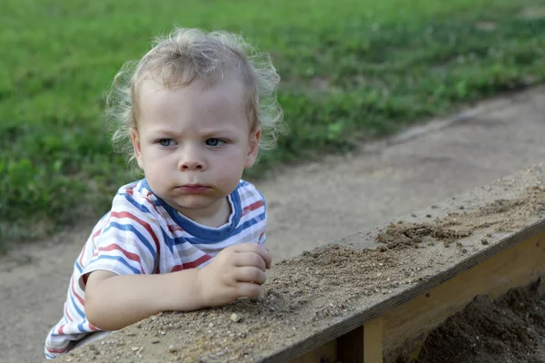 Серьезный ребенок в песочнице — стоковое фото
