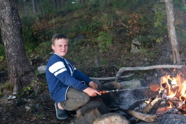Çocuk ormanda ateşte ekmek kızartıyor, Karelia.