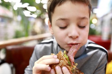 Restoranda hamburger yiyen çocuk portresi