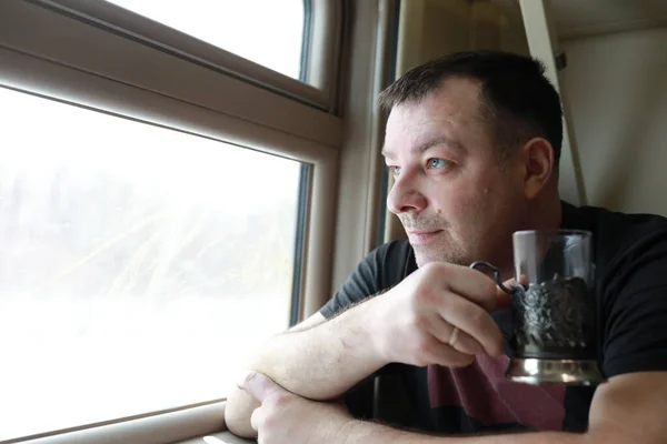 窓の横で電車の中でお茶を飲む男 — ストック写真