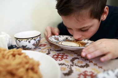 Kafedeki çay tabağından çay içen çocuk