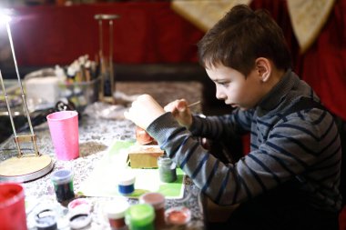 Çocuk atölyede seramik oyuncak boyuyor.