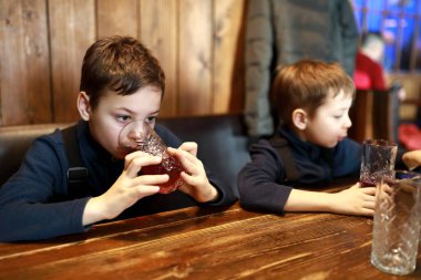 İki çocuk bir restoranda meyve suyu içiyor.