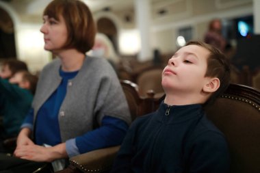 Anne ve oğlu tiyatroda gösteri izliyorlar.