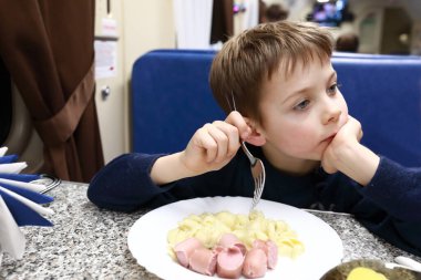 Restoran vagonunda sosisli makarna yiyen çocuk.