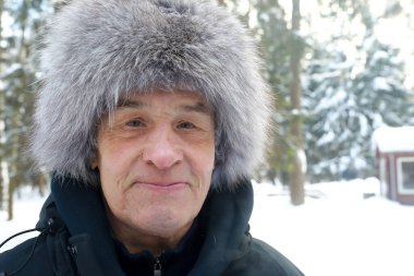 Kış parkında kürk şapkalı yaşlı adamın portresi.