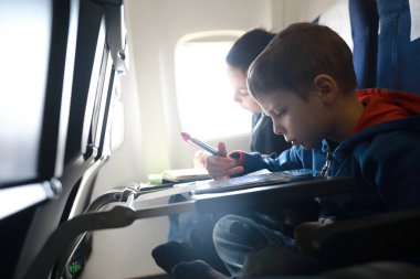 Çocuklar uçuş sırasında uçakta resim çizerler.