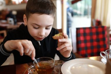 Lokantada çörekle çay içen çocuk.
