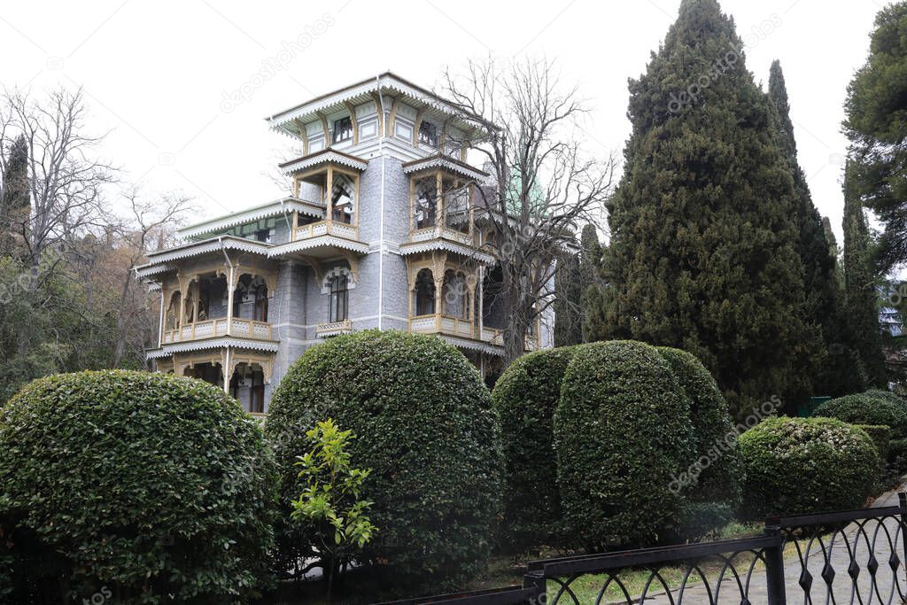 View of house with wooden balcony in Gurzuf park in spring