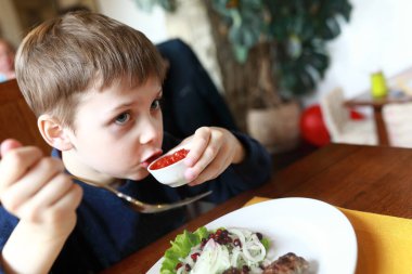 Restoranda domates sosu tatmış çocuk.