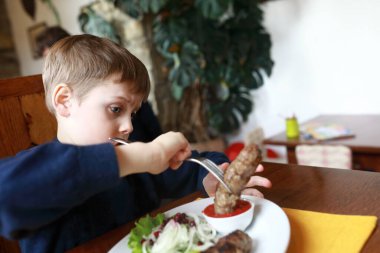 Lokantada dana eti yiyen çocuk.