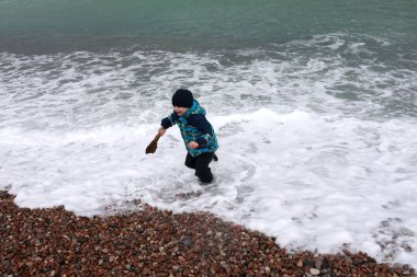 Çocuk baharda Gurzuf sahilinde dalgalardan kaçıyor.