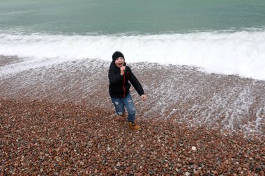 Çocuk baharda Gurzuf sahilinde dalgalardan kaçıyor.