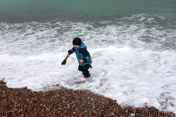 Çocuk baharda Gurzuf sahilinde dalgalardan kaçıyor.