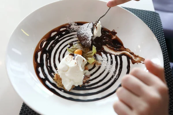 Person eating chocolate fondant in a restaurant