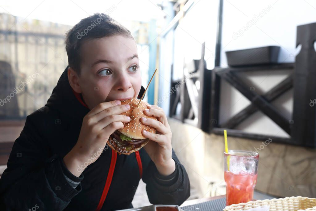 Child eating burger on restaurant terrace in spring