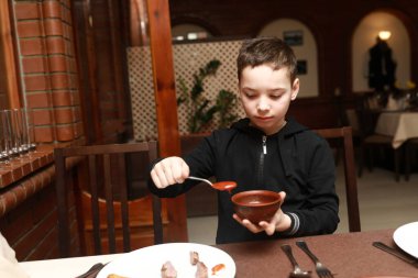 Restoranda domates sosu alan bir çocuk.