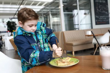 Restoranda krep yiyen bir çocuk.