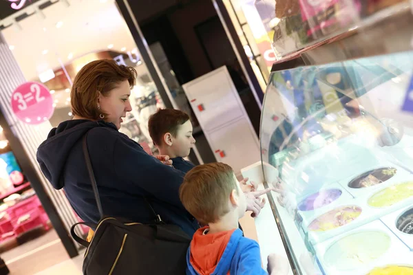 店内でアイスクリームを選ぶ息子の母親 — ストック写真