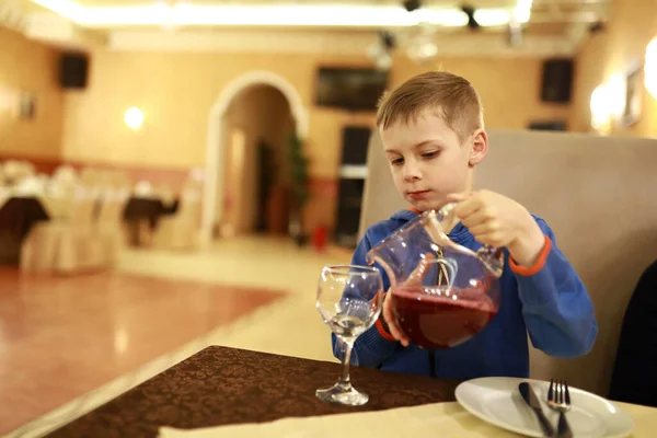 Portrait of child pouring juice in restaurant